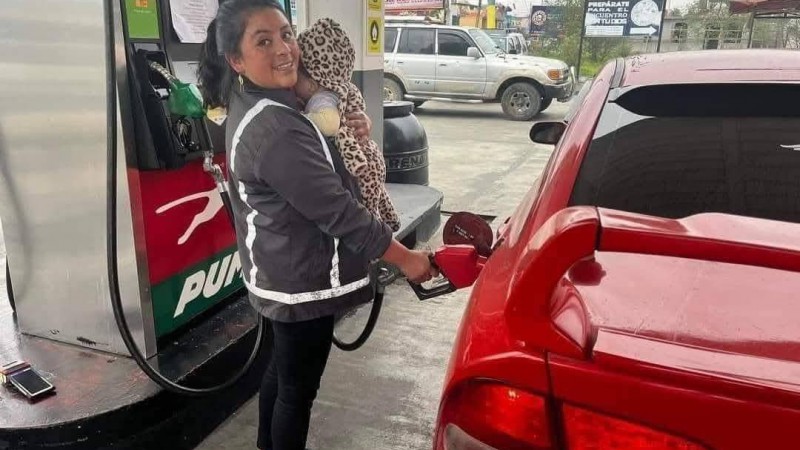 Una madre trabaja en una estación de servicio con su bebé en brazos